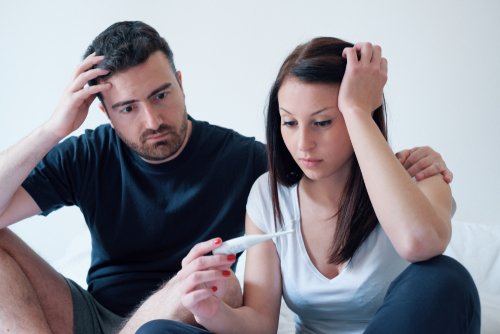 Male and female looking with worry at a pregnancy test