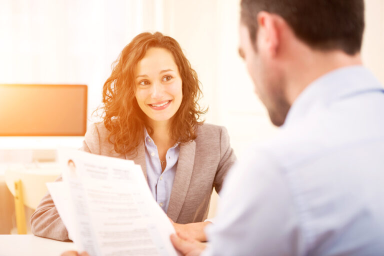 Male looking at a resume of a young woman sitting in front of him